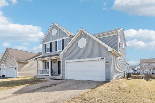 traditional-style house featuring a porch, cooling unit, a garage, and driveway