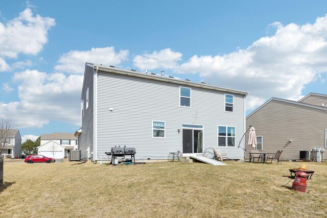 rear view of house with central AC unit and a lawn