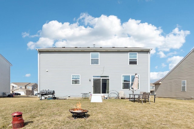 rear view of house featuring an outdoor fire pit and a yard