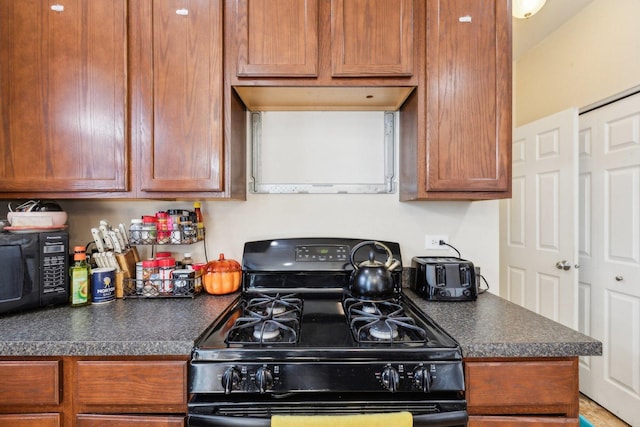 kitchen with black appliances, brown cabinetry, and dark countertops