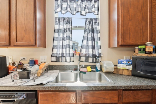 kitchen with dark countertops, black microwave, dishwasher, brown cabinetry, and a sink