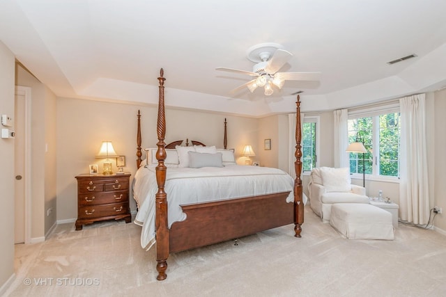 bedroom with light carpet, baseboards, visible vents, and a raised ceiling