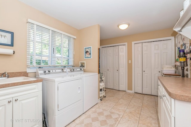 clothes washing area with light tile patterned floors, independent washer and dryer, a sink, and cabinet space