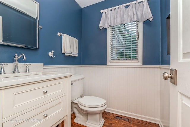 bathroom with toilet, wainscoting, wood finished floors, and visible vents