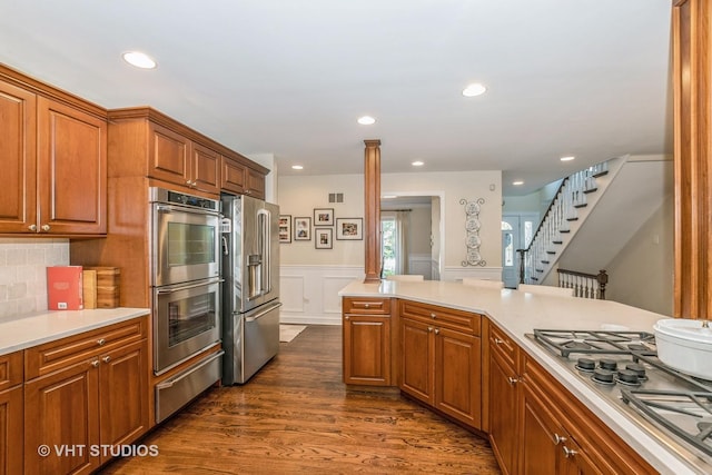 kitchen featuring a warming drawer, stainless steel appliances, brown cabinetry, and light countertops