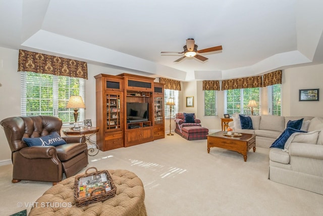 carpeted living room with ceiling fan, a tray ceiling, and a healthy amount of sunlight