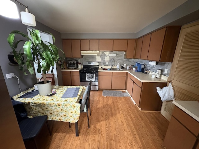 4257 W SW Hwy, Hometown, IL 60456 - kitchen with light wood-style floors, gas range, light countertops, under cabinet range hood, and a sink