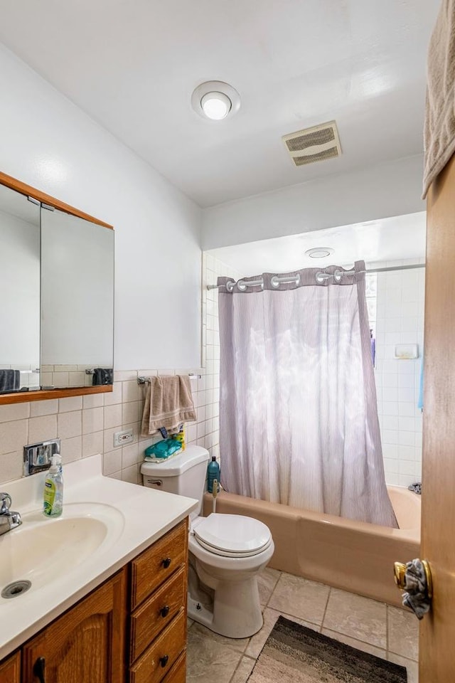 bathroom with visible vents, toilet, shower / bath combination with curtain, vanity, and tile walls