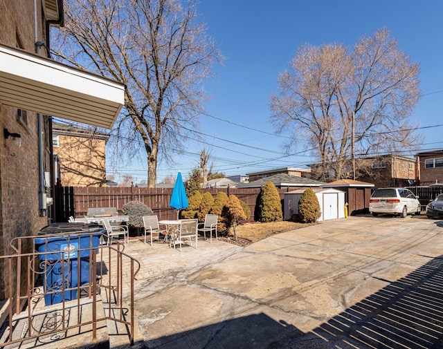 view of patio / terrace featuring outdoor dining area, an outdoor structure, a storage shed, and fence