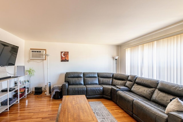 living room with a wall unit AC and light wood-style flooring