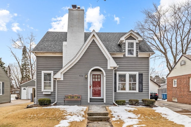 view of front facade with a garage, a shingled roof, and a chimney