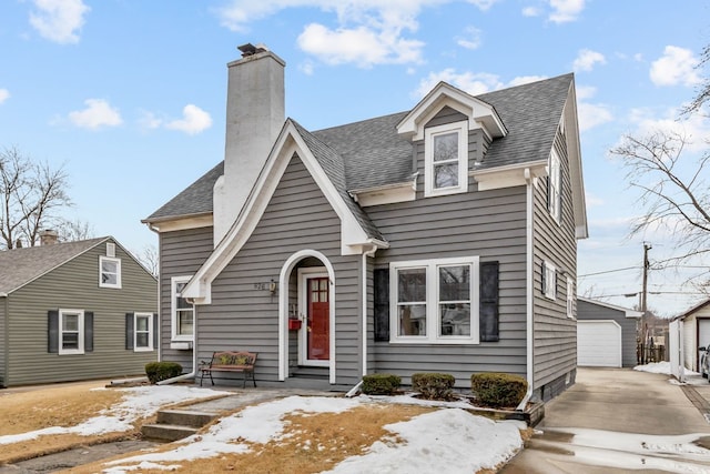 view of front of house with a garage, a shingled roof, a chimney, and an outdoor structure