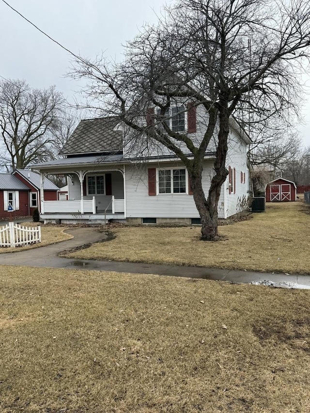 view of front of home featuring covered porch, a shed, a front lawn, and an outdoor structure