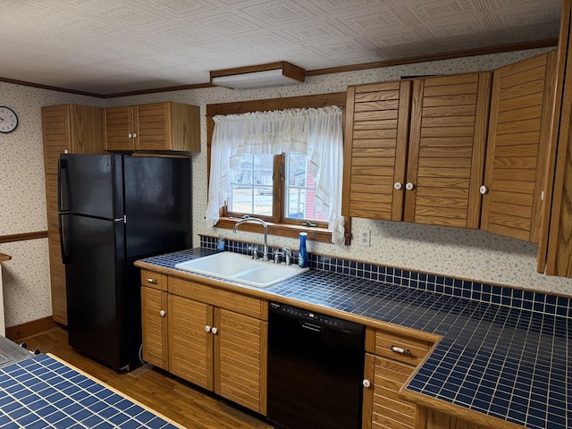 kitchen with an ornate ceiling, tile counters, black appliances, and wallpapered walls