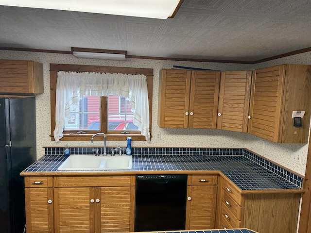 kitchen with a sink, tile countertops, black appliances, and wallpapered walls