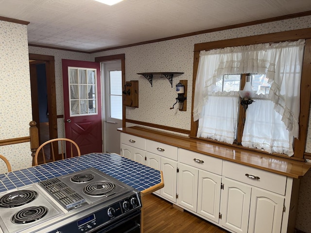 kitchen with electric range, dark wood-style flooring, white cabinets, ornamental molding, and wallpapered walls