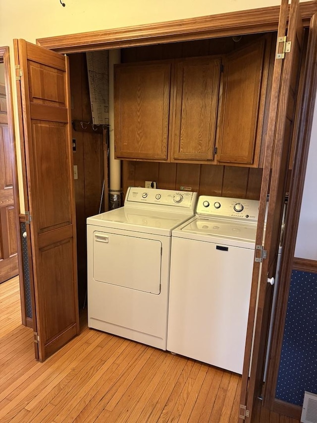 laundry area with visible vents, cabinet space, washer and clothes dryer, and light wood finished floors