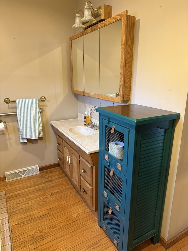 bathroom with baseboards, visible vents, wood finished floors, and vanity