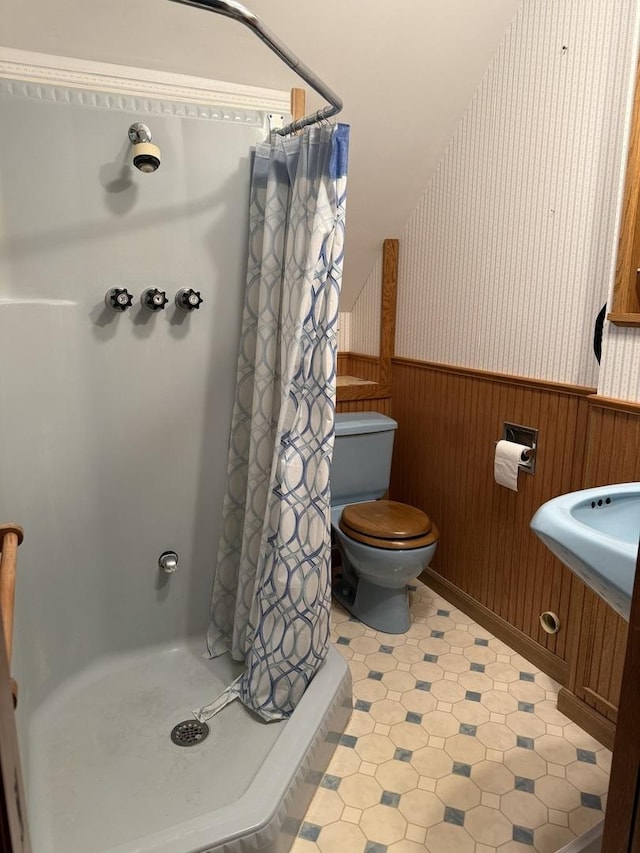 full bath featuring a wainscoted wall, toilet, a stall shower, wooden walls, and tile patterned floors