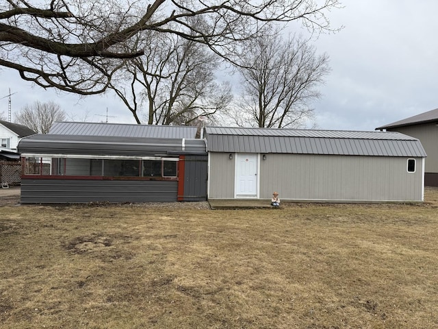 back of house featuring metal roof and a yard