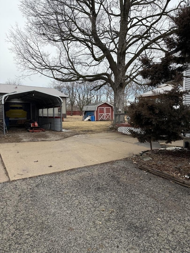 view of yard featuring a detached carport, gravel driveway, an outdoor structure, and a shed