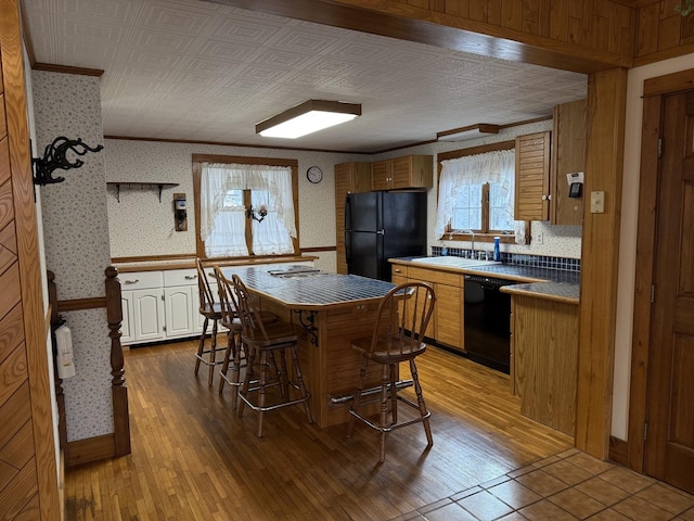 kitchen featuring black appliances, wallpapered walls, and crown molding