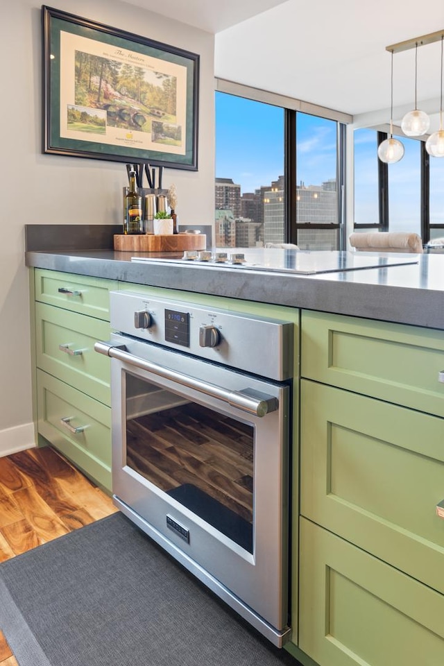 kitchen with a view of city, green cabinets, wood finished floors, and oven