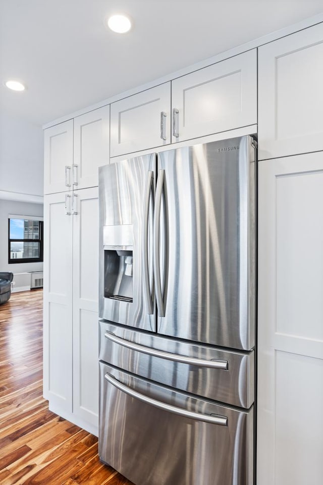 kitchen with recessed lighting, white cabinetry, wood finished floors, and stainless steel fridge with ice dispenser