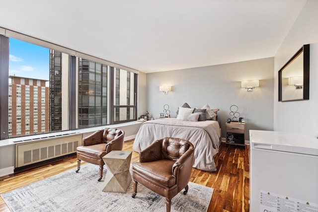 bedroom with radiator heating unit, wood finished floors, and baseboards