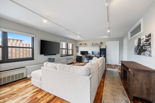 living room featuring radiator, track lighting, and wood finished floors