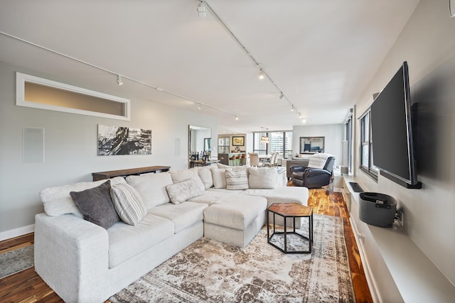 living area with baseboards, track lighting, and wood finished floors