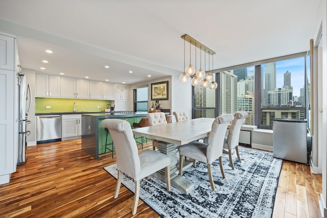 dining area featuring a view of city, a chandelier, wood finished floors, and recessed lighting