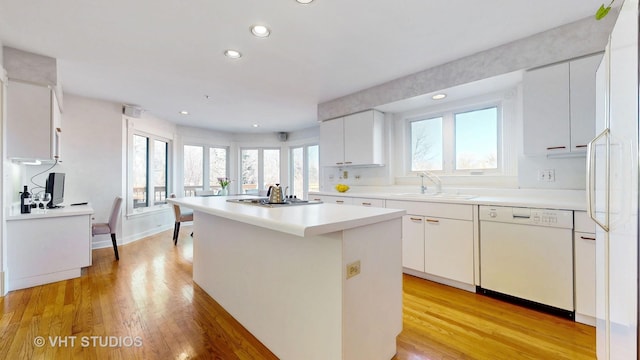 kitchen featuring light wood-style floors, white dishwasher, a kitchen island, and a sink