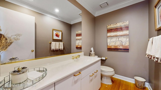 bathroom with toilet, wood finished floors, vanity, baseboards, and ornamental molding