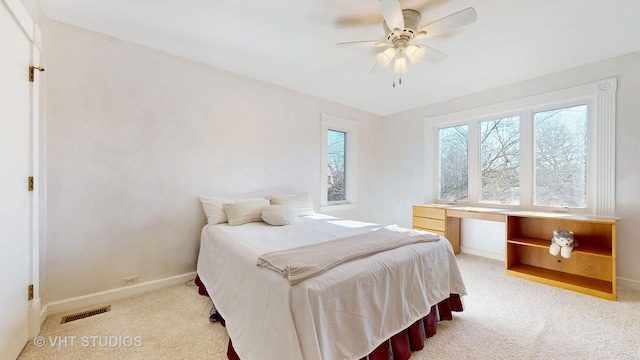 bedroom with light carpet, baseboards, visible vents, a ceiling fan, and built in study area