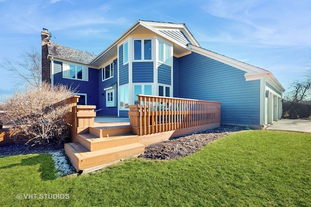 rear view of property featuring a yard, a chimney, a deck, a garage, and driveway