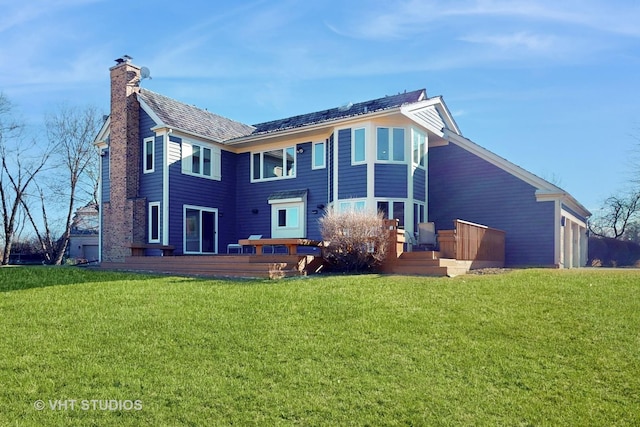 rear view of property with a chimney, a deck, and a yard