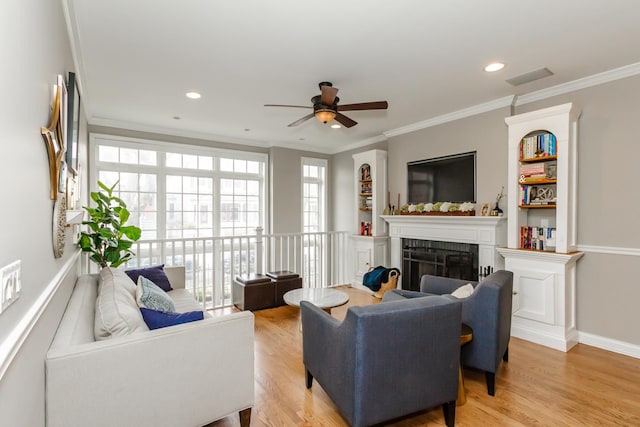 living area featuring light wood-style floors, a fireplace, ornamental molding, and recessed lighting