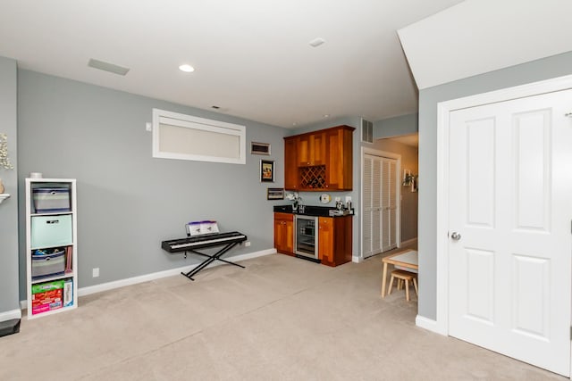 kitchen featuring beverage cooler, dark countertops, baseboards, and light colored carpet