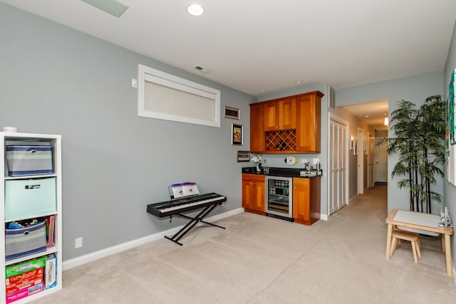 kitchen with light carpet, beverage cooler, baseboards, brown cabinetry, and dark countertops