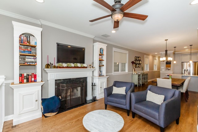 living room featuring recessed lighting, a fireplace, visible vents, ornamental molding, and light wood-type flooring