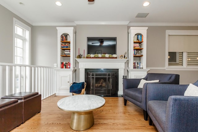 living area featuring light wood finished floors, a premium fireplace, ornamental molding, and recessed lighting