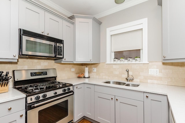 kitchen featuring appliances with stainless steel finishes, light countertops, a sink, and ornamental molding