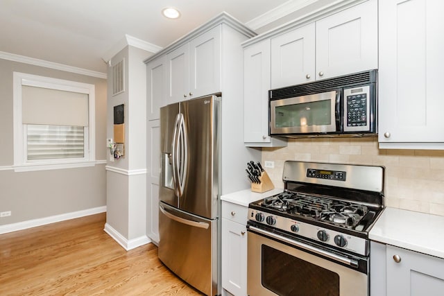 kitchen featuring crown molding, light countertops, decorative backsplash, appliances with stainless steel finishes, and baseboards