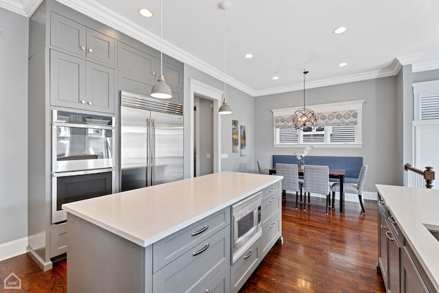 kitchen featuring gray cabinets, crown molding, dark wood-style flooring, and built in appliances