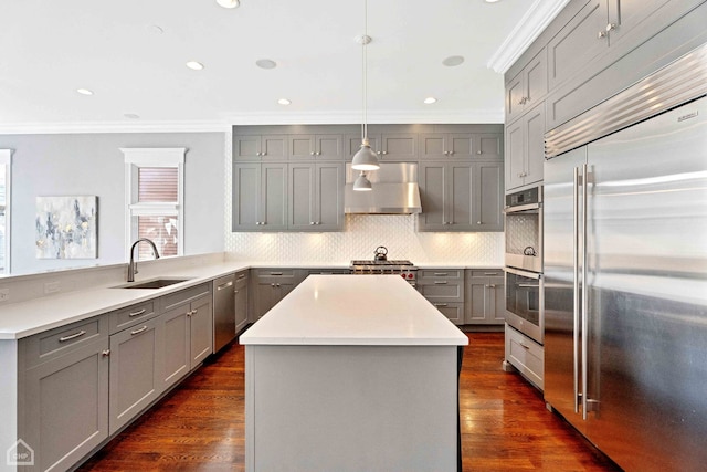 kitchen with crown molding, gray cabinetry, appliances with stainless steel finishes, a sink, and under cabinet range hood