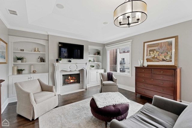 living area with a tray ceiling, visible vents, and built in features