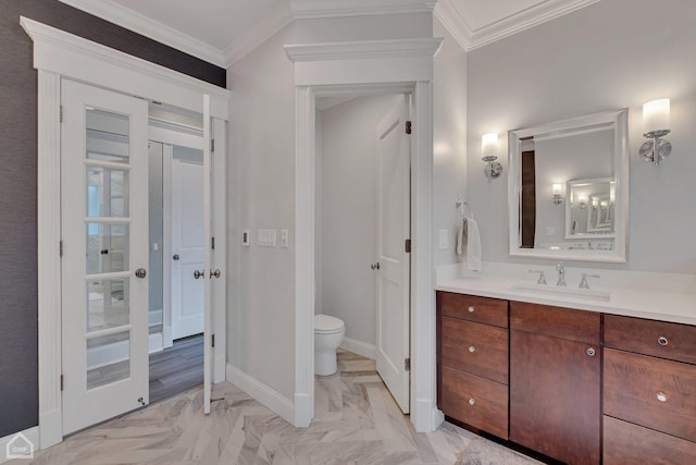 bathroom featuring toilet, marble finish floor, crown molding, and vanity