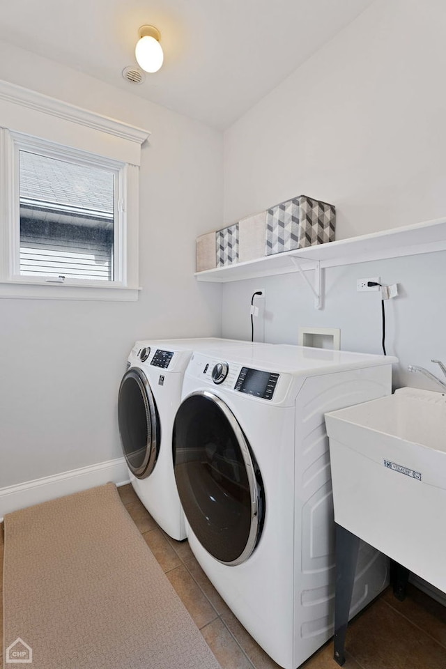 clothes washing area with light tile patterned floors, a sink, separate washer and dryer, laundry area, and baseboards