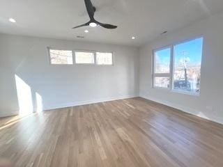 empty room with a wealth of natural light, ceiling fan, baseboards, and wood finished floors